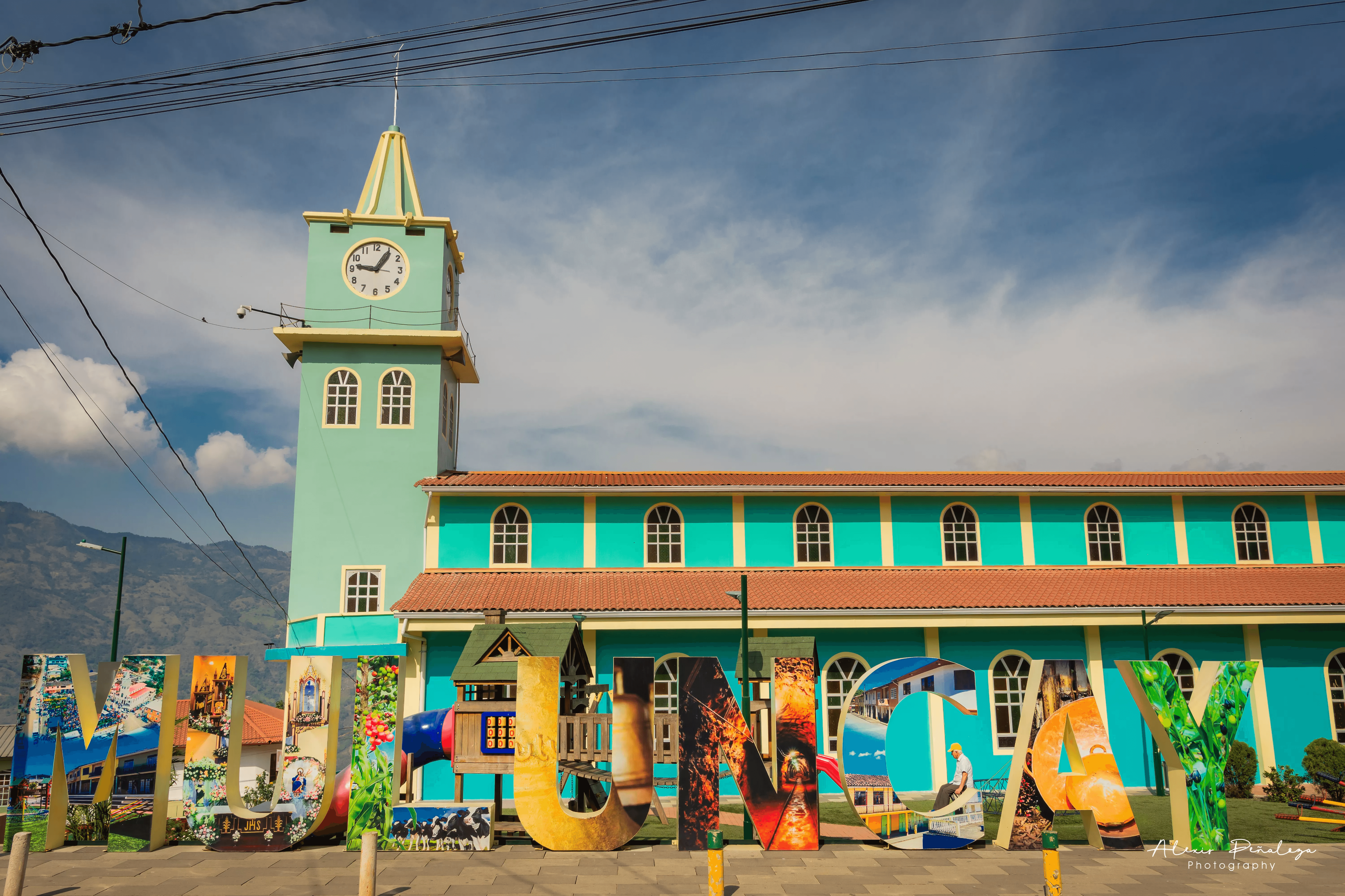 Letras turísticas coloridas de Muluncay frente a la iglesia del pueblo