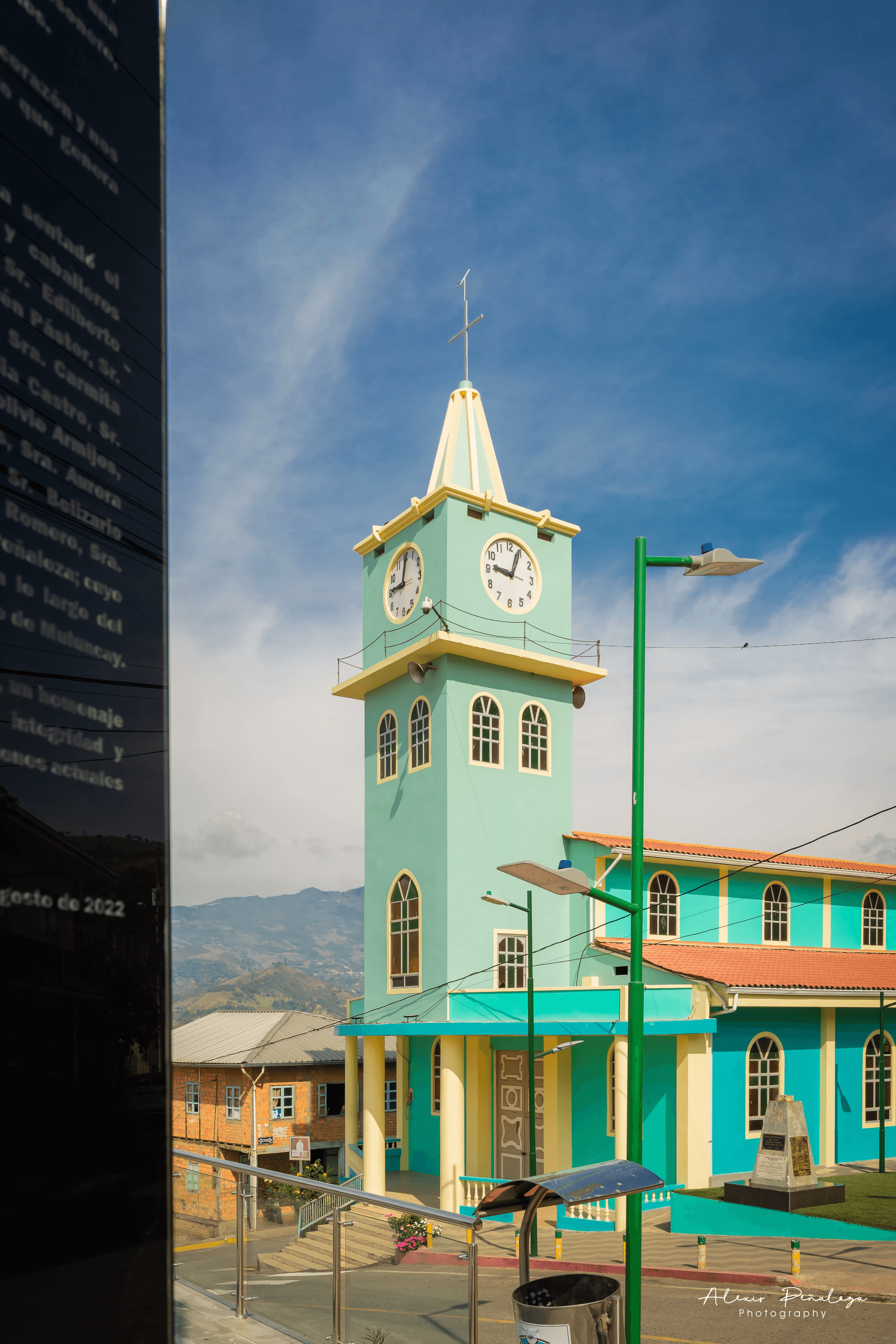 Vista de la iglesia turquesa parcialmente enmarcada por un muro oscuro
