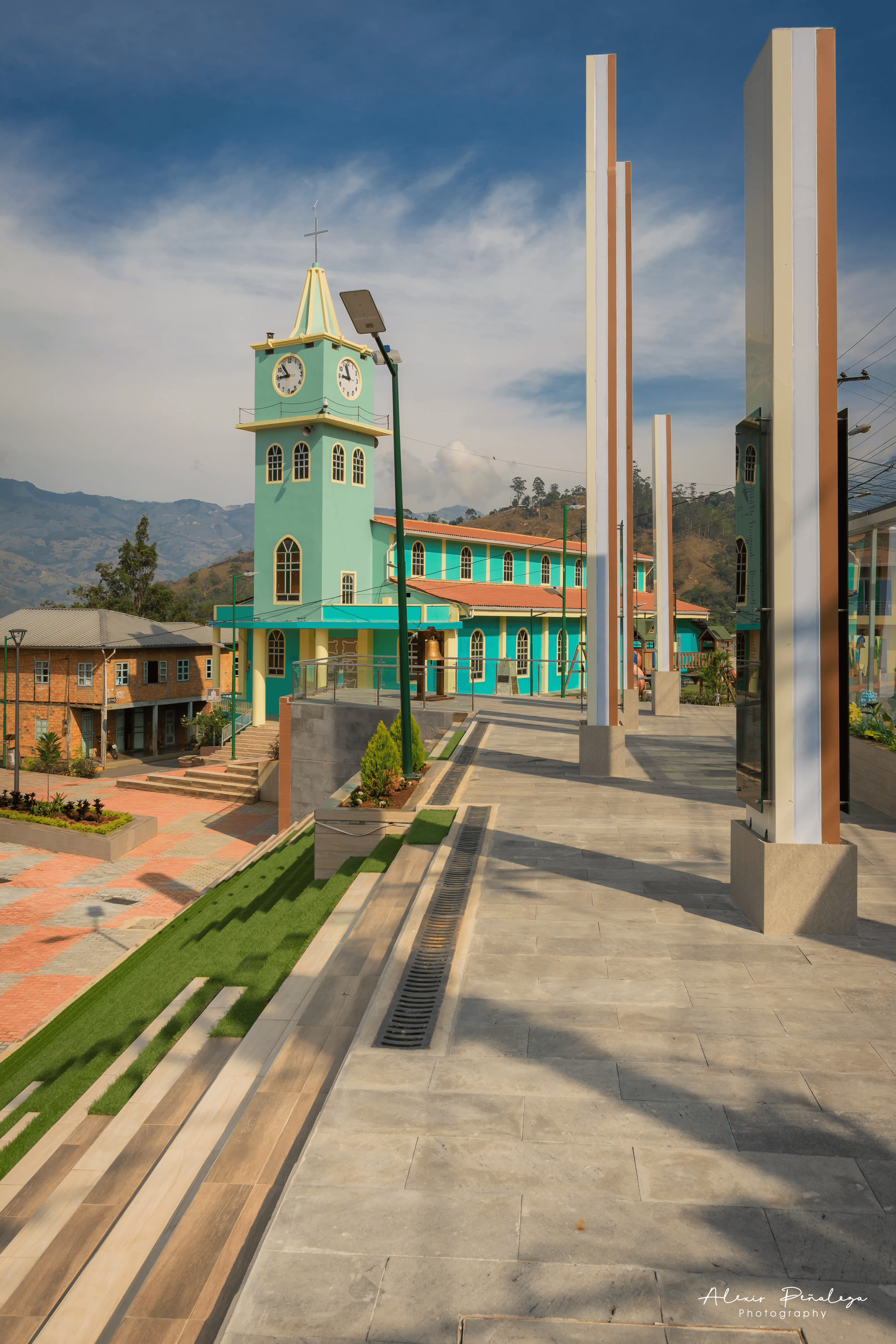 Plaza moderna de Muluncay con gradas verdes e iglesia