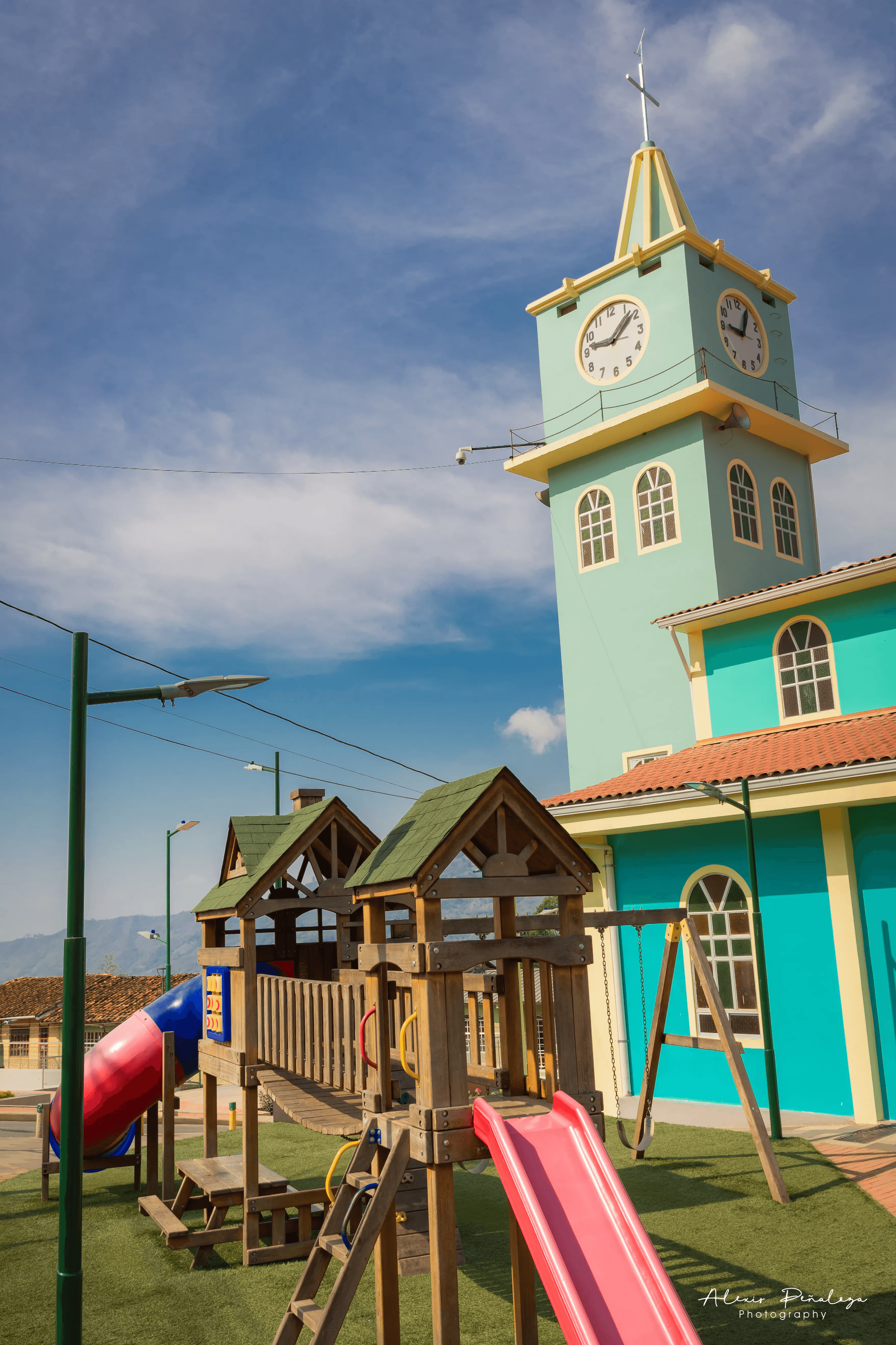 Estructura de juegos infantiles de madera bajo el campanario de la iglesia