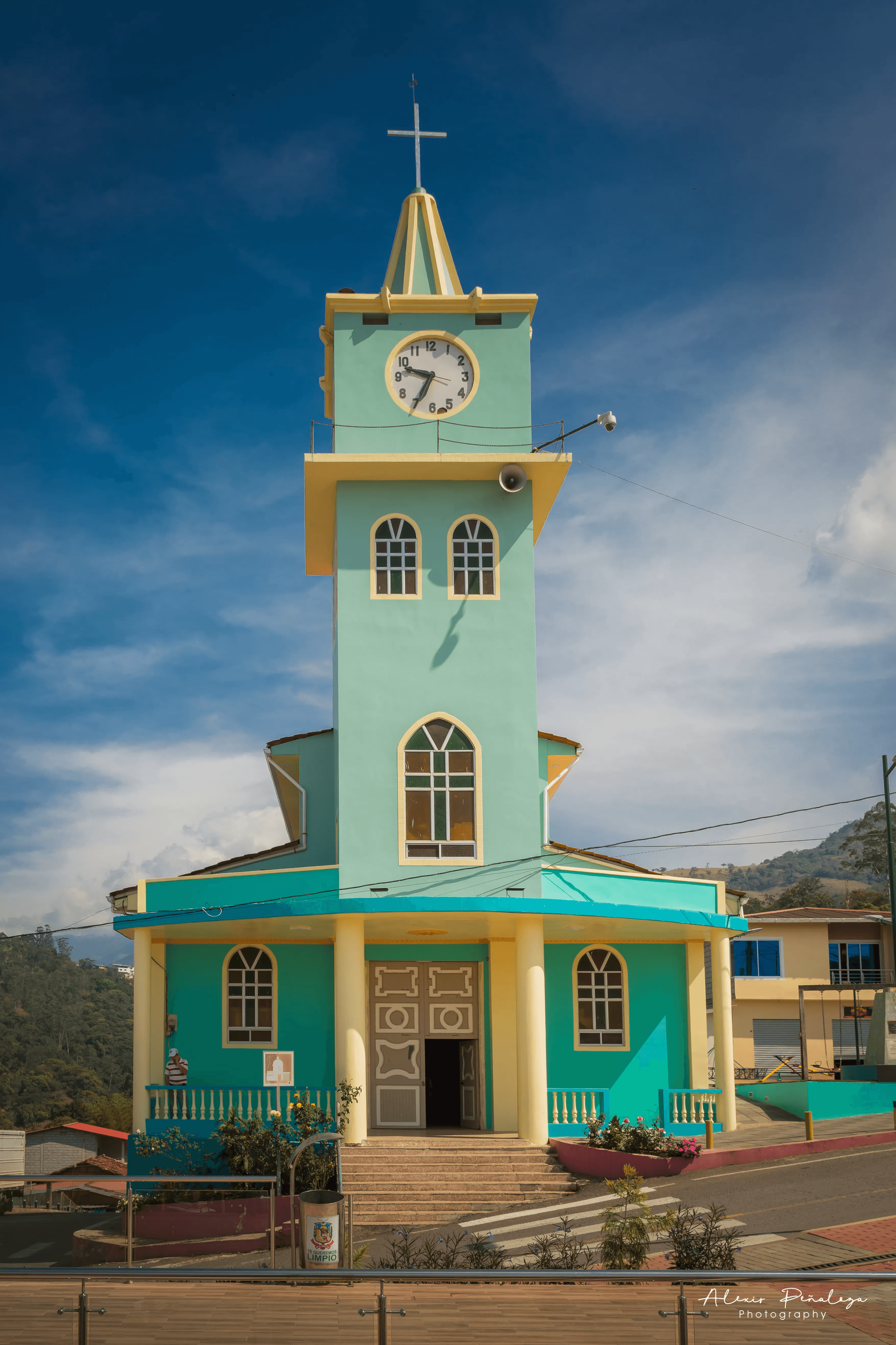 Fachada turquesa, techo y campanario central de la iglesia del pueblo